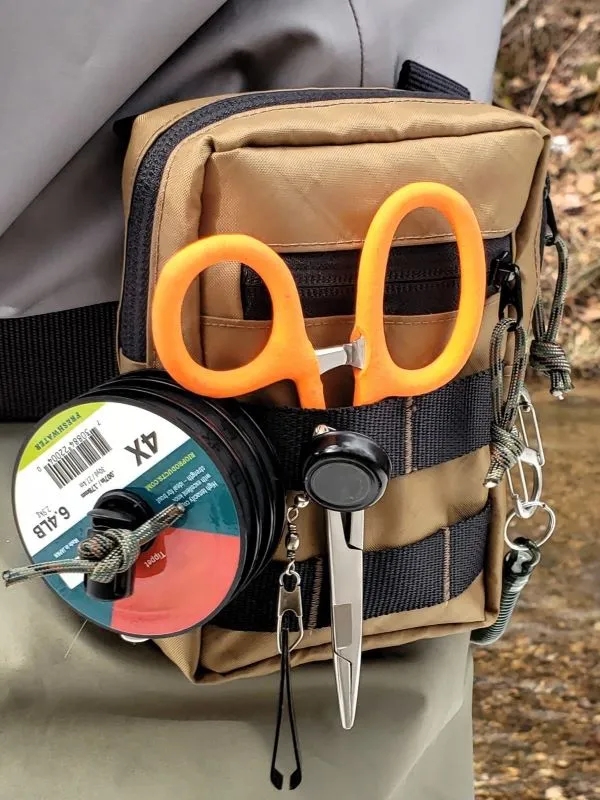 A fly fishing pack on the belt of a fly fisherman.