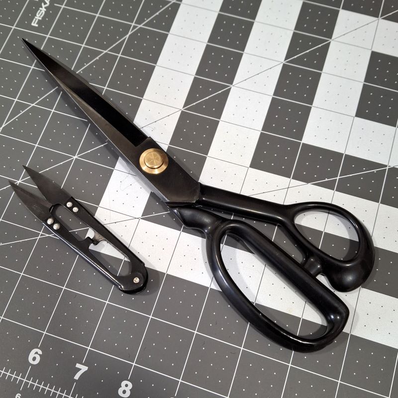 Fabric shears and thread snips on a cutting mat.