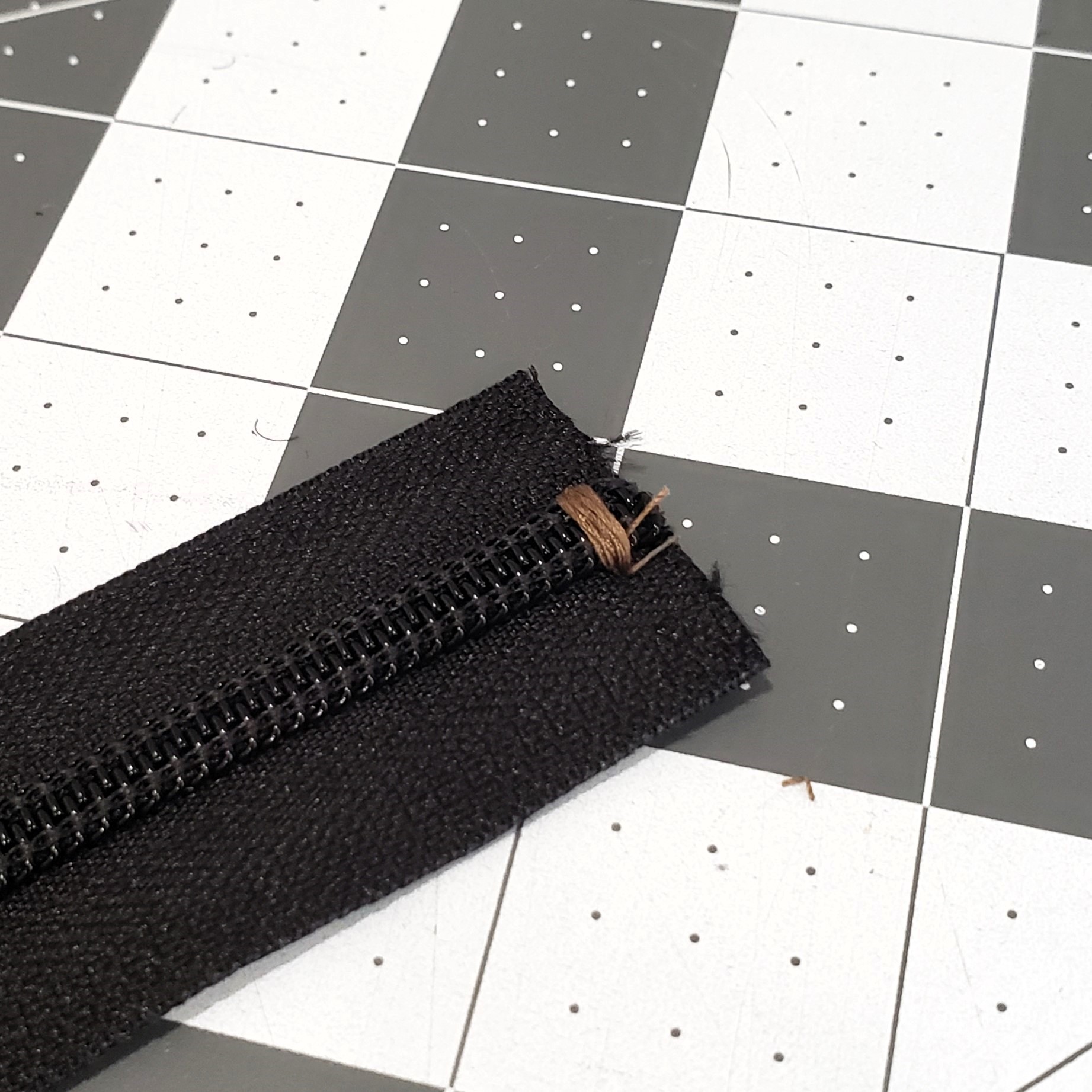 Zipper coil with bar-tacked end