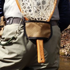 A fly fisher wearing a net holster with a net in the pouch