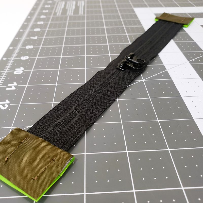 An assembled zipper with tabs on each end and sliders instealled.