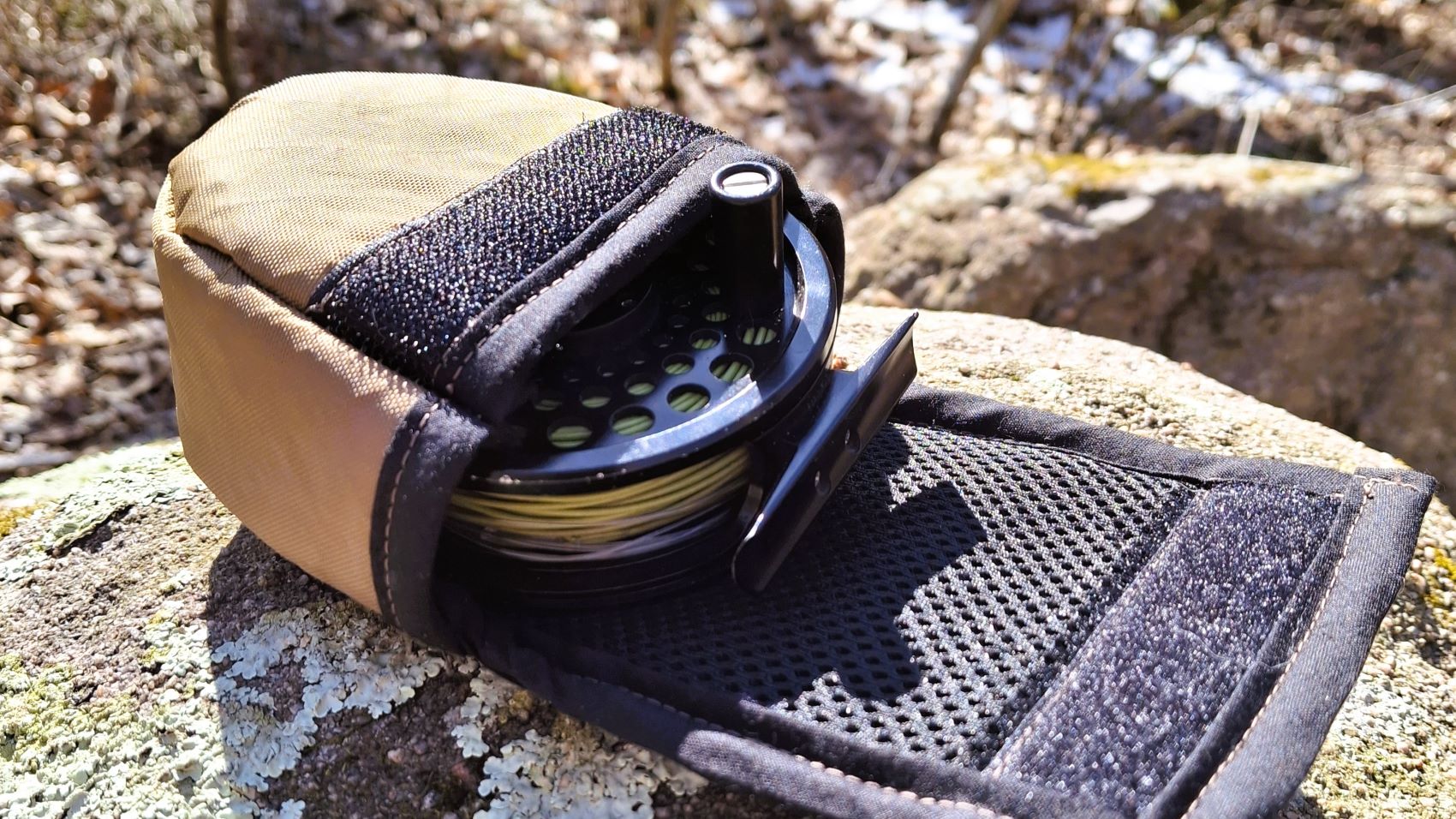 Flylight reel cover open and sitting on a rock.